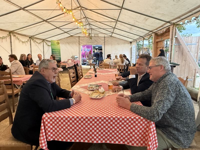 Gäste im Gespräch an der langen Tafel unterm Zeltdach.
