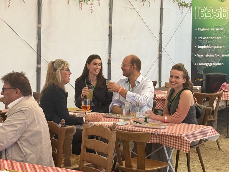 Unternehmerinnen und Unternehmer im Gespräch am Tisch im Biergarten.